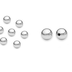 May include: A set of silver-colored metal beads. The beads are round and smooth. There are 10 beads in total, with two larger beads on the right side of the image.