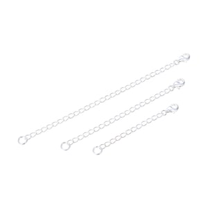 May include: Three silver chain extenders of different lengths. Each extender has a lobster clasp on one end and a jump ring on the other.