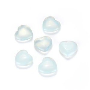 May include: Six translucent, light blue heart-shaped stones on a white background.