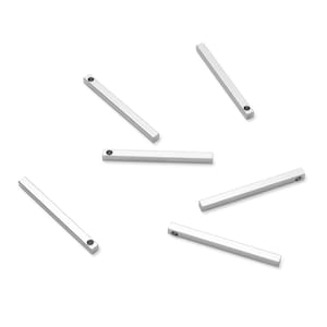 May include: Six silver metal bar charms with a small hole at one end. The bars are all the same size and shape.