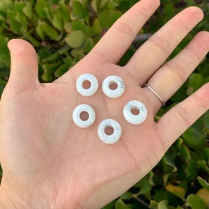 May include: Five white howlite donut beads with a hole in the center. The beads are smooth and have a marbled pattern.
