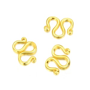 May include: Three gold-toned metal S-shaped clasps for jewelry making. The clasps are designed to be used as a closure for necklaces, bracelets, or other jewelry.