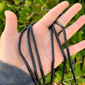 May include: A strand of black beads, made of small, round, and cylindrical beads. The beads are strung on a thin wire and are approximately 10 inches long.