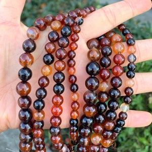 May include: A strand of brown, orange, and black agate beads. The beads are round and have a polished finish.