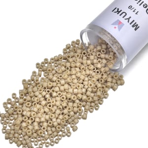 May include: A clear plastic tube of Miyuki Delica beads, size 11/0, spilling onto a white surface. The beads are a light beige color and cylindrical in shape, ideal for jewelry making and beadwork projects.