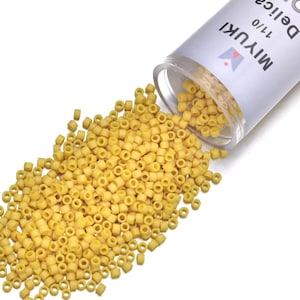 May include: Yellow Miyuki Delica seed beads, size 11/0, spilling from a clear plastic container. The beads are small, cylindrical, and have a consistent shape. The container has the brand name "MIYUKI" printed on it.