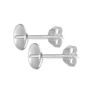 Puede incluir: Un par de postes de pendientes de plata con una parte superior redonda y plana. Los postes están diseñados para sujetar un dije u otra joya.