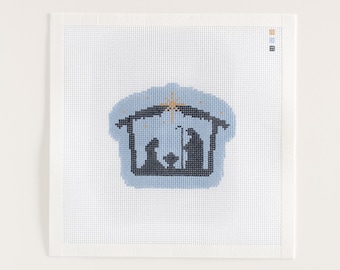 Könnte beinhalten: Ein Kreuzstich-Design mit einer Krippenszene. Das Bild zeigt einen Stall in hellblauer Farbe mit einem Stern darüber. Die Figuren im Stall sind dunkelblau. Der Kreuzstich befindet sich auf einer weißen Leinwand.
