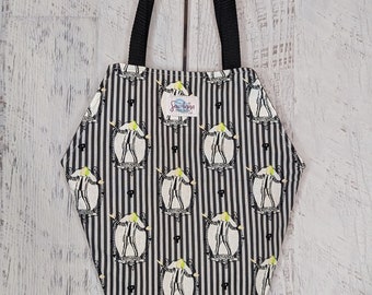 May include: Black and white striped tote bag with a coffin shape. The bag has a repeating pattern of a skeleton figure in a circle with the text "This is Halloween" inside the circle. The bag has black straps.