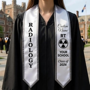 May include: A black graduation gown with a white and grey Radiology sash. The sash includes the text "Custom Name", "RT", a radiation symbol, "Your School", and "Class of 2026". The word "Radiology" is printed vertically on the other side.