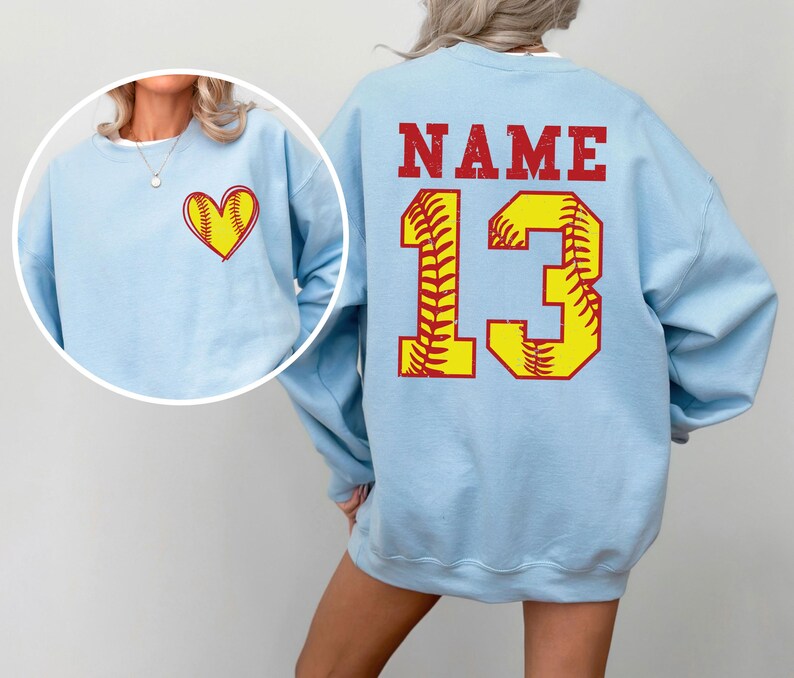 a woman wearing a light blue sweatshirt with a softball design on it