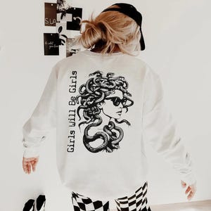 a woman wearing a white sweatshirt and checkered pants