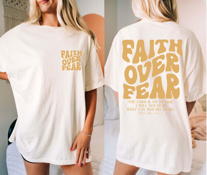 Puede incluir: Camiseta color crema con las palabras "FAITH OVER FEAR" en una fuente retro en la parte delantera y trasera. La parte trasera tambi&eacute;n incluye el texto "THE LORD IS ON MY SIDE, I WILL NOT FEAR, WHAT CAN MAN DO TO ME? PSALMS 118:6."