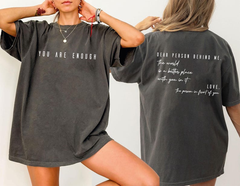 a person wearing a gray t-shirt with the text "You are enough" printed on it.