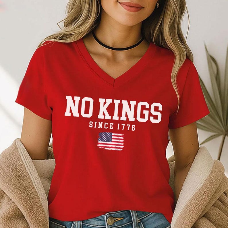 A woman wearing a red t-shirt with the text "NO KINGS SINCE 1776" and an American flag graphic.