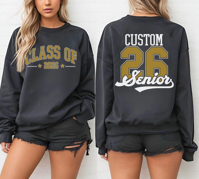 A woman wearing a black sweatshirt with the text "CLASS OF" and "26 Senior" printed on it, along with a number "26" and a letter "S" printed below.