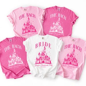 a collection of pink and white t-shirts with the text "The Bach" and "Bridal" printed on them, along with a castle illustration.