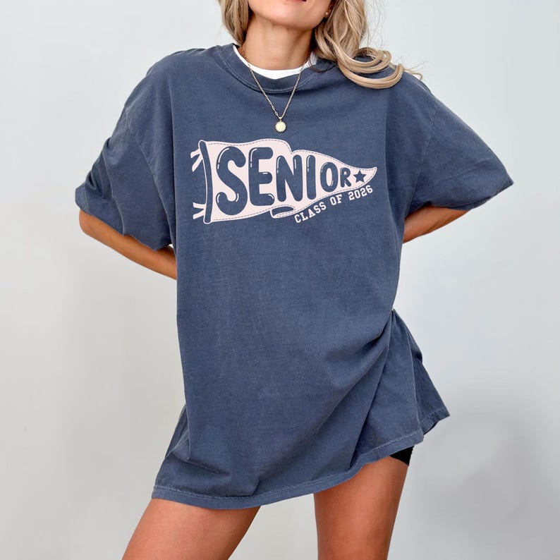 A woman wearing a blue t-shirt with the text "SENIOR CLASS OF 2026" printed on it.