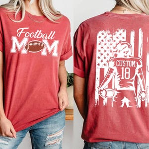 A red t-shirt with the text "Football Mom" printed on it, along with an image of a football player wearing a helmet with the number 18.