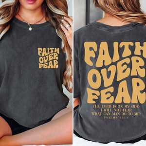 a woman sitting on a bed wearing a shirt that says faith over fear