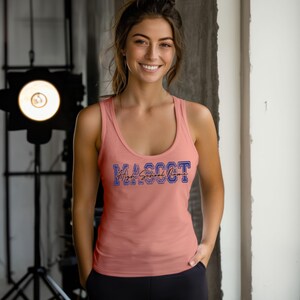 A smiling woman wearing a pink tank top with the word "Mascot" printed on it, standing in front of a light source.