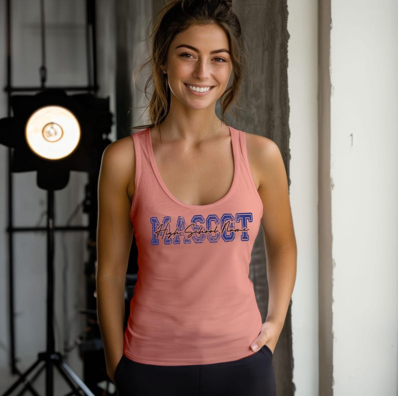 A smiling woman wearing a pink tank top with the word "Mascot" printed on it, standing in front of a light source.