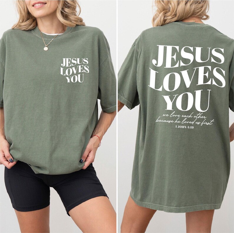 A woman wearing a green t-shirt with the text "JESUS LOVES YOU" printed on it.