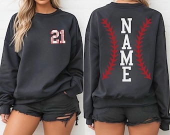 May include: Dark grey sweatshirt. The front displays the number 21 in a baseball design. The back features the word "NAME" in white block letters, framed by red baseball stitching.