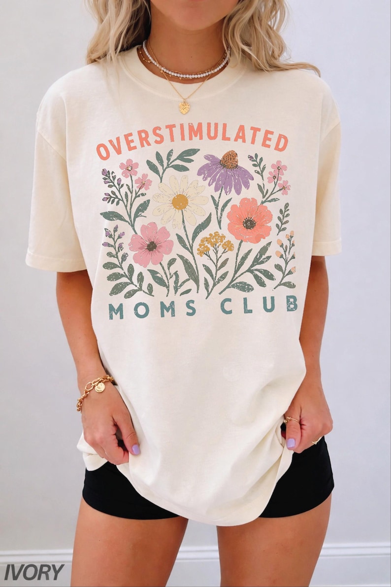 A woman wearing a white t-shirt with a floral design and text printed on it.