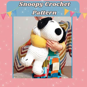 May include: A crocheted Snoopy doll with black ears and a black spot on its face is being held. The doll is white with black accents. The text "Snoopy Crochet Pattern" is at the top of the image. The background includes a colorful blanket and a child's clothing.