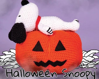 May include: A crocheted Halloween decoration featuring Snoopy lying on an orange pumpkin. The pumpkin has a carved jack-o'-lantern face. Snoopy is white with black ears and a black spot on his head, wearing a red collar. The text "Halloween Snoopy" is at the bottom.