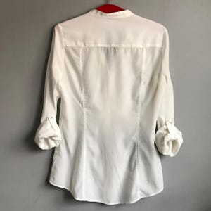 May include: White long-sleeve button-down shirt with a mandarin collar.