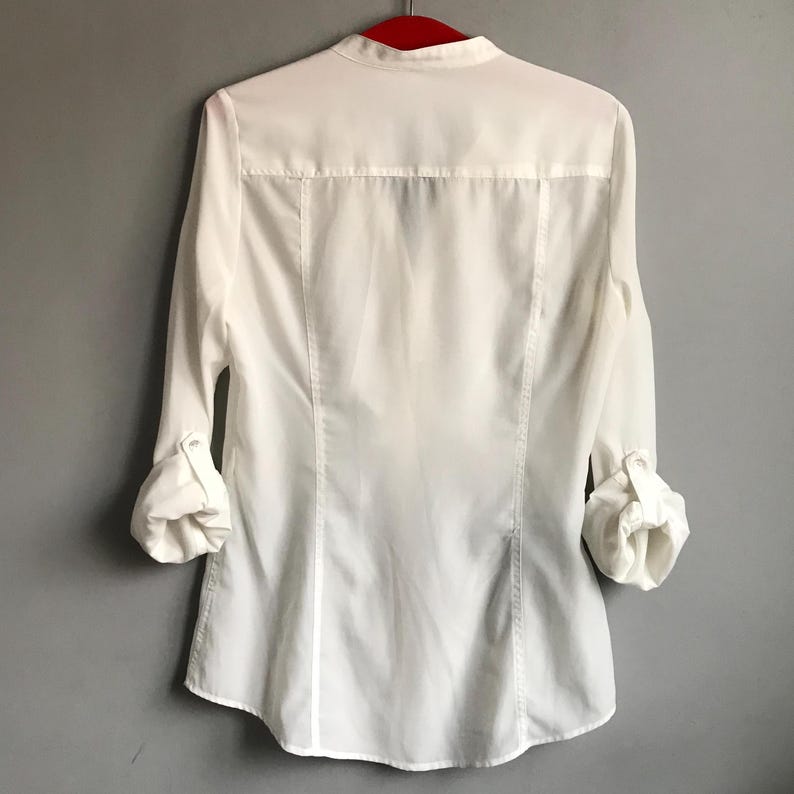 May include: White long-sleeve button-down shirt with a mandarin collar.