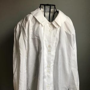 Pu&ograve; includere: Una camicia bianca a maniche lunghe con bottoni, colletto e maniche leggermente a sbuffo. La camicia &egrave; realizzata in tessuto testurizzato e ha una vestibilit&agrave; rilassata.