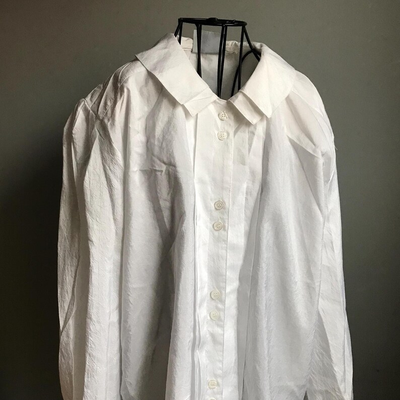 Pu&ograve; includere: Una camicia bianca a maniche lunghe con bottoni, colletto e maniche leggermente a sbuffo. La camicia &egrave; realizzata in tessuto testurizzato e ha una vestibilit&agrave; rilassata.