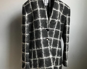 Könnte beinhalten: Ein schwarz-weiß kariertes Blazer mit einer flauschigen Textur. Der Blazer hat einen V-Ausschnitt und drei Knöpfe.