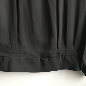 May include: Black, pleated, long-sleeved blouse with a gathered neckline.