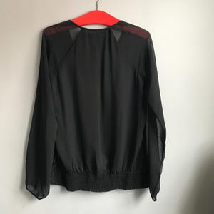 May include: Black sheer long-sleeve blouse with a gathered elastic waistband.
