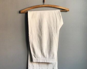 May include: White striped pants hanging on a wooden hanger. The pants are folded in half and have a relaxed fit.