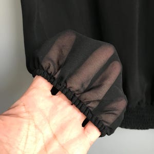 May include: Black sheer fabric with a gathered elastic band at the bottom. The fabric is translucent and has a soft, flowing texture.