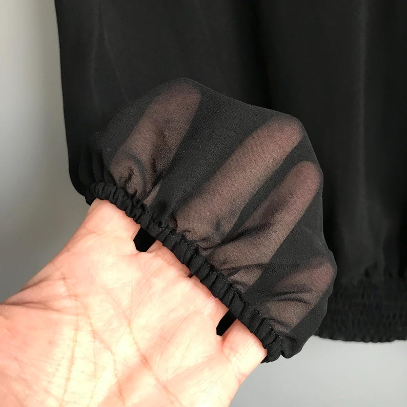May include: Black sheer fabric with a gathered elastic band at the bottom. The fabric is translucent and has a soft, flowing texture.