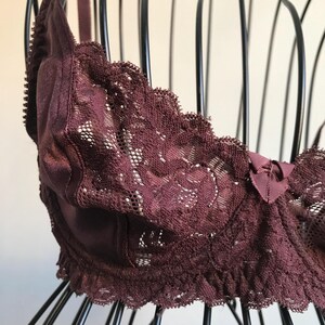 May include: A burgundy lace bra with a satin cup and a bow detail.