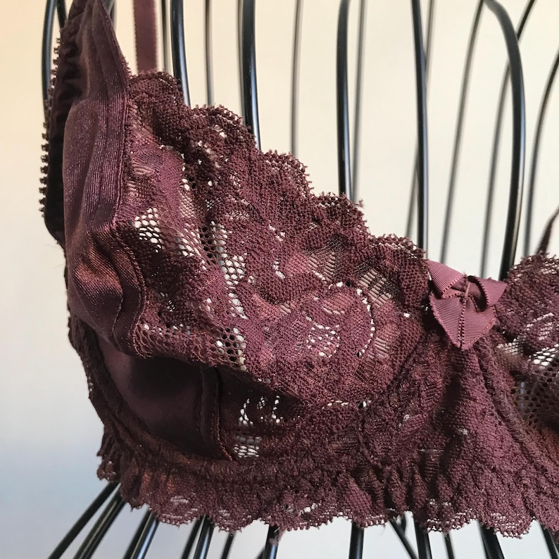 May include: A burgundy lace bra with a satin cup and a bow detail.