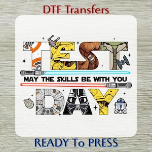 May include: A white square DTF transfer featuring Star Wars characters and text. The word "TEST DAY" is spelled out with character-themed letters. The phrase "MAY THE SKILLS BE WITH YOU" is written below the word "TEST". The words "READY TO PRESS" are at the bottom.