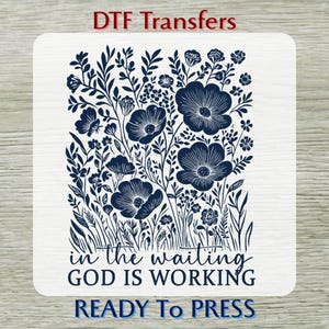 May include: A white DTF transfer with a navy blue floral design. The design features large flowers and foliage, with the text "in the waiting GOD IS WORKING" and "READY To PRESS".
