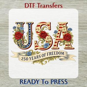 May include: DTF Transfers graphic featuring the word "USA" in red, white, and blue, adorned with floral accents and the text "250 YEARS OF FREEDOM." The design is ready to press.