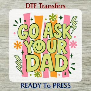 May include: A square DTF transfer with the text "GO ASK YOUR DAD" in a lime green font, featuring a smiley face and decorative elements. The background has pink and orange vertical stripes. The words "DTF Transfers" and "READY To PRESS" are also present.