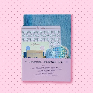 Op de afbeelding: Een journal starter kit met een map met denimtextuur die een vel alfabetstickers, een holografische sticker en diverse papieren bevat. Het lichtpaarse label aan de voorzijde vermeldt de inhoud, waaronder plakpapier, alfabetstickers, clips en notitieblaadjes.