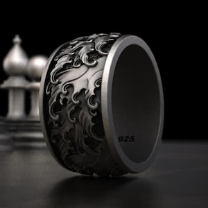 May include: A silver ring with a detailed design of stylized waves. The ring is marked with "925" on the inside.