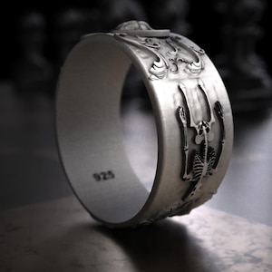 Pu&ograve; includere: Un anello d'argento con un design dettagliato a scheletro. L'anello presenta una superficie strutturata e il numero "925" &egrave; visibile. L'anello ha un motivo intricato ed &egrave; probabilmente realizzato in argento sterling.